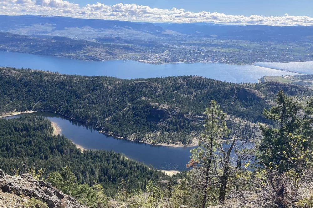 Looking down on the Hayman Lake Loop trail, this view captures the tranquil curves of the lake framed by dense pine forests and cliffs.